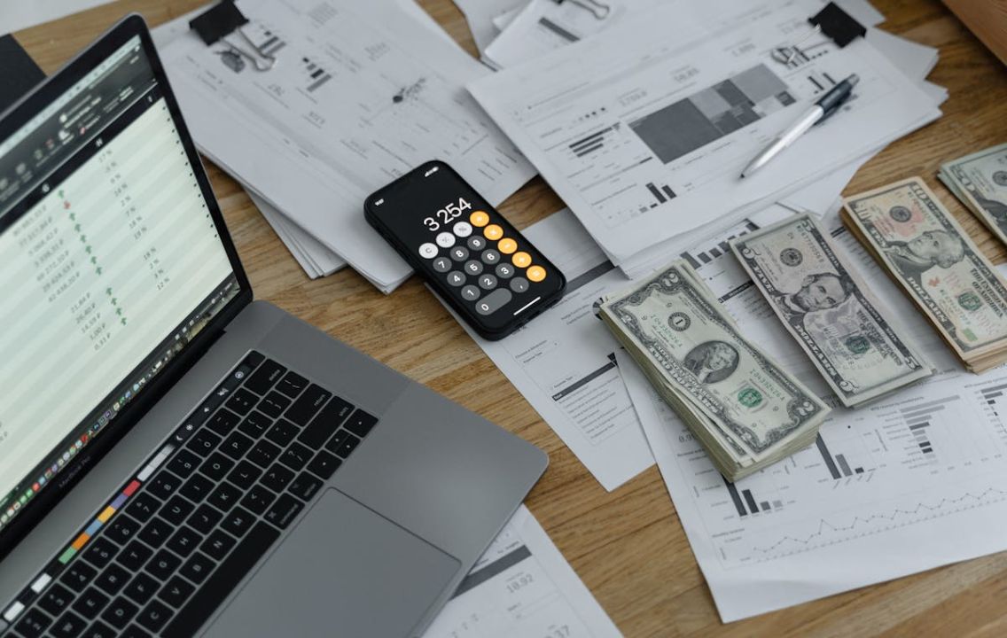 Financial documents, calculator, laptop, and planning notes on a desk