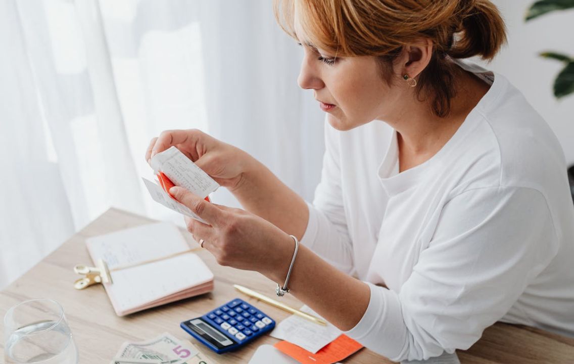 Woman reviewing a personal budget with a laptop and cash
